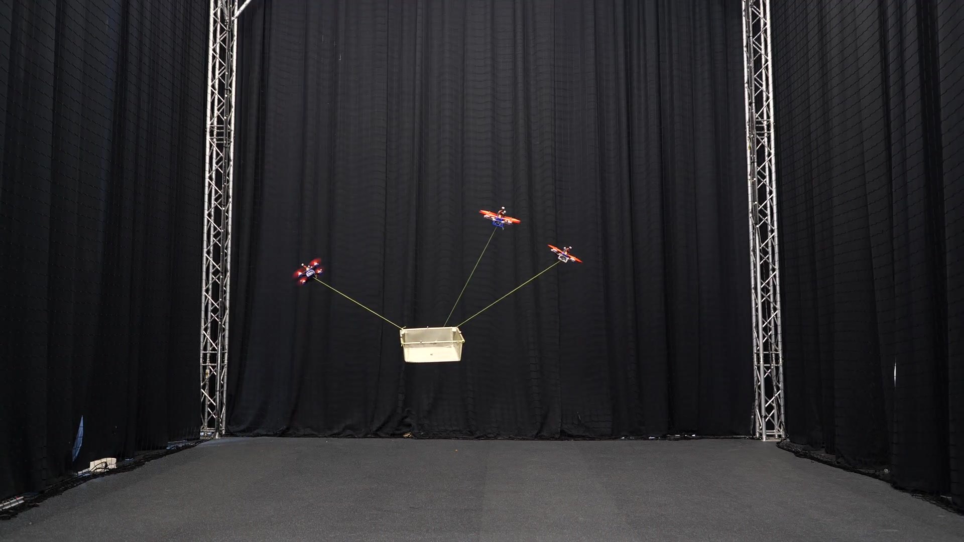 Three drones carrying a load together in the arena (photo 2 of 7)